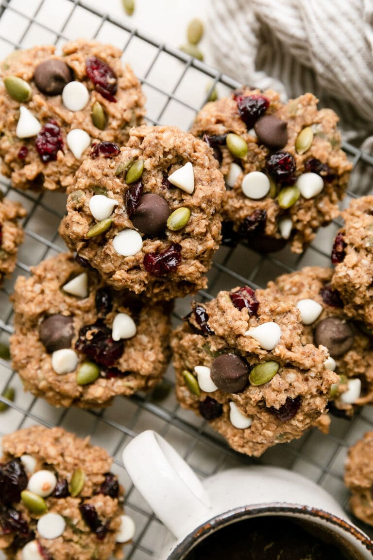 Overhead view of trail mix breakfast cookies on a cooling rack beside a cup of coffee. 